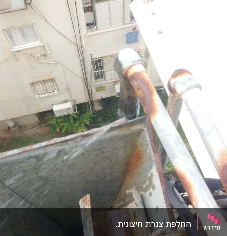 צינורות חלודים עם מים זורמים מגג בניין